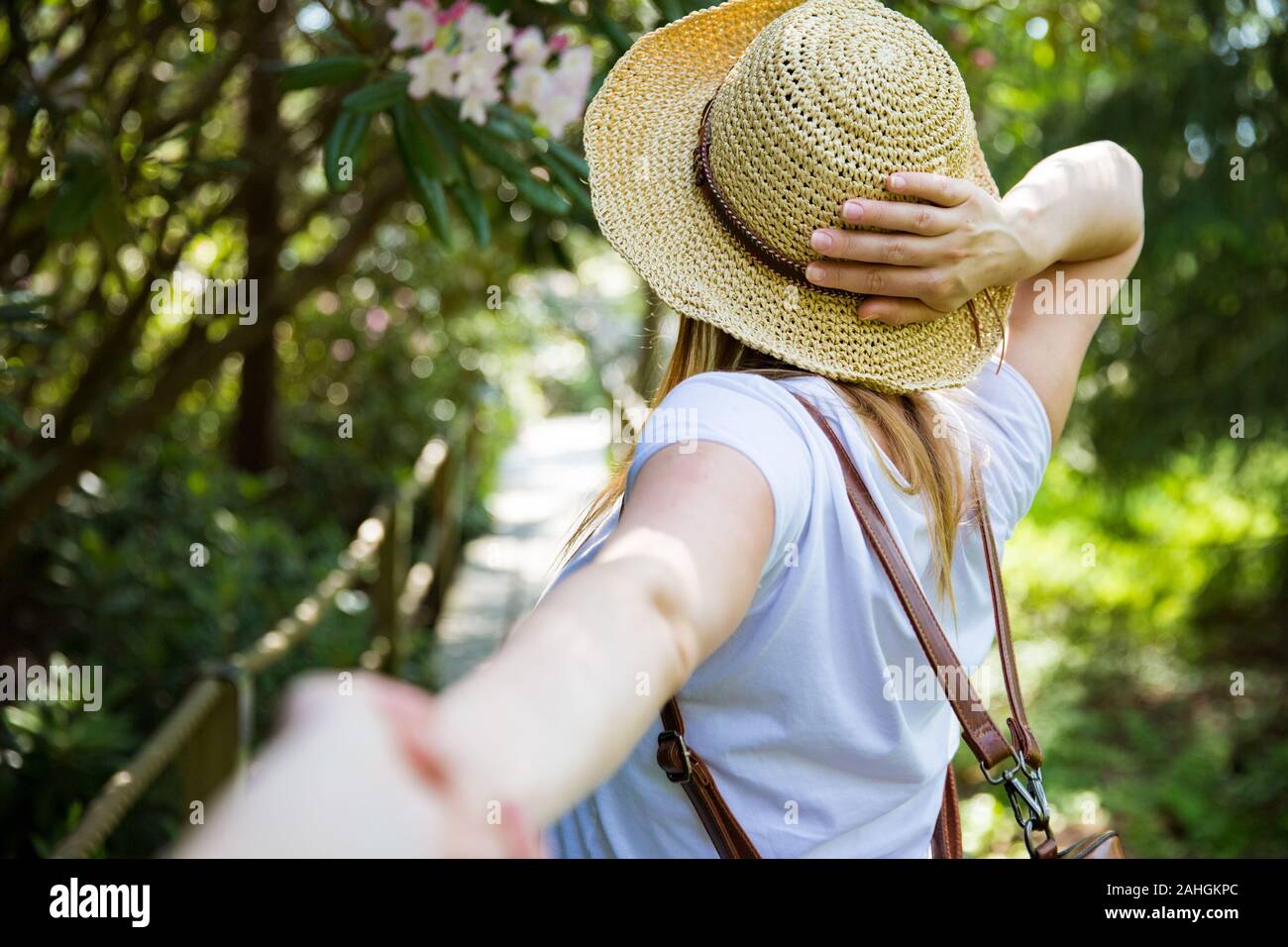 Belle femme en chapeau de paille voyage dans la forêt tropicale, marchant  le long du chemin en bois, dirigeant son partenaire. Tourisme avec sac à  dos. Suivez-moi le concept Photo Stock -