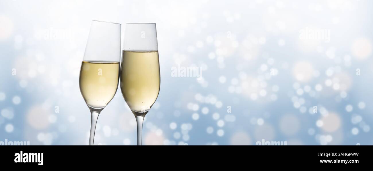 Bonne année 2020, deux flûtes de champagne toasting contre un léger flou d'arrière-plan, bulle bleue partie concept en format panoramique avec spa de copie Banque D'Images