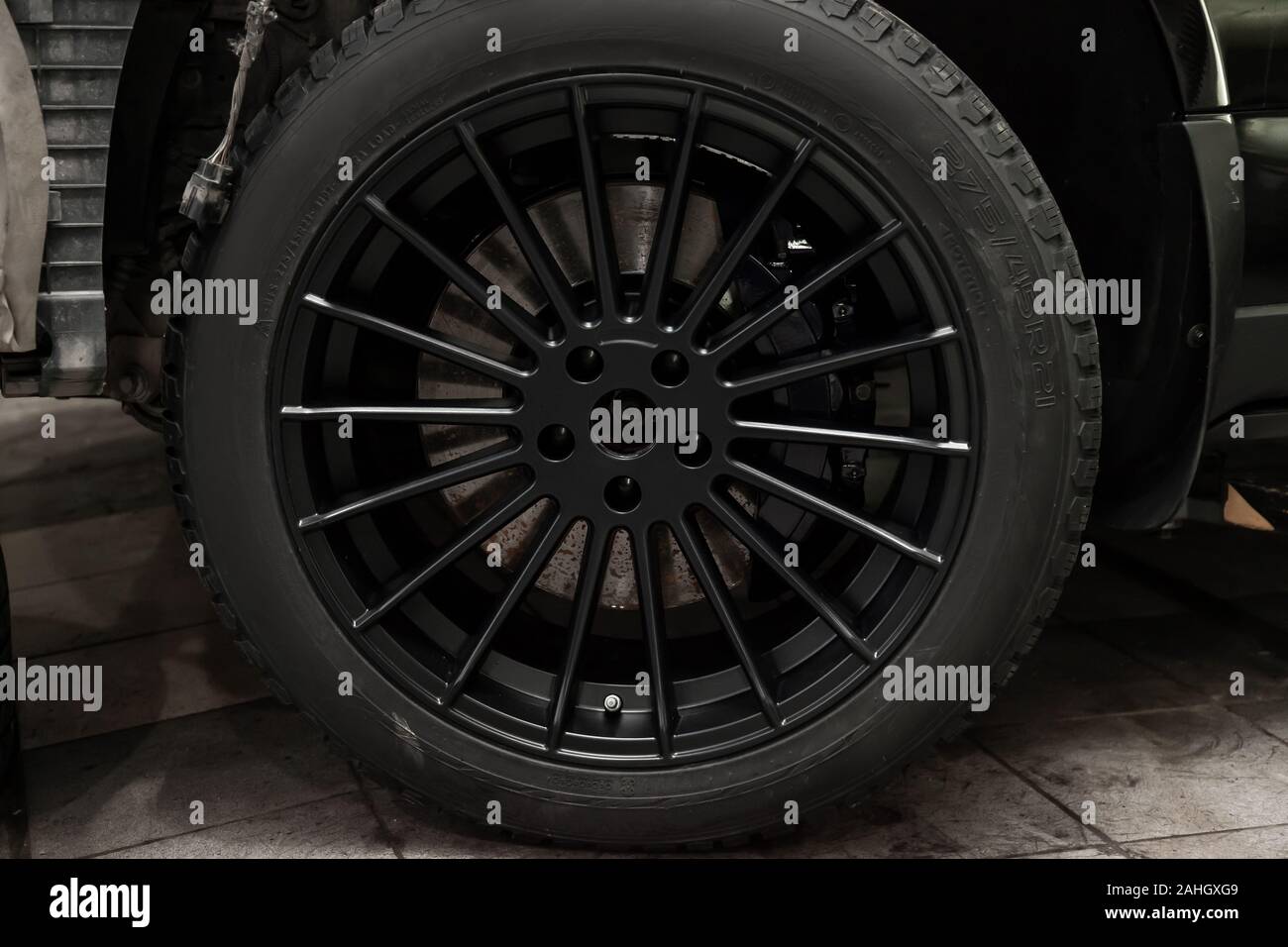 Un alliage d'aluminium roue R21 avec pneus cloutés d'hiver sur une voiture  noire avec un nouveau disque de frein nécessitant un remplacement. La météo  et les transports. Auto service Photo Stock -
