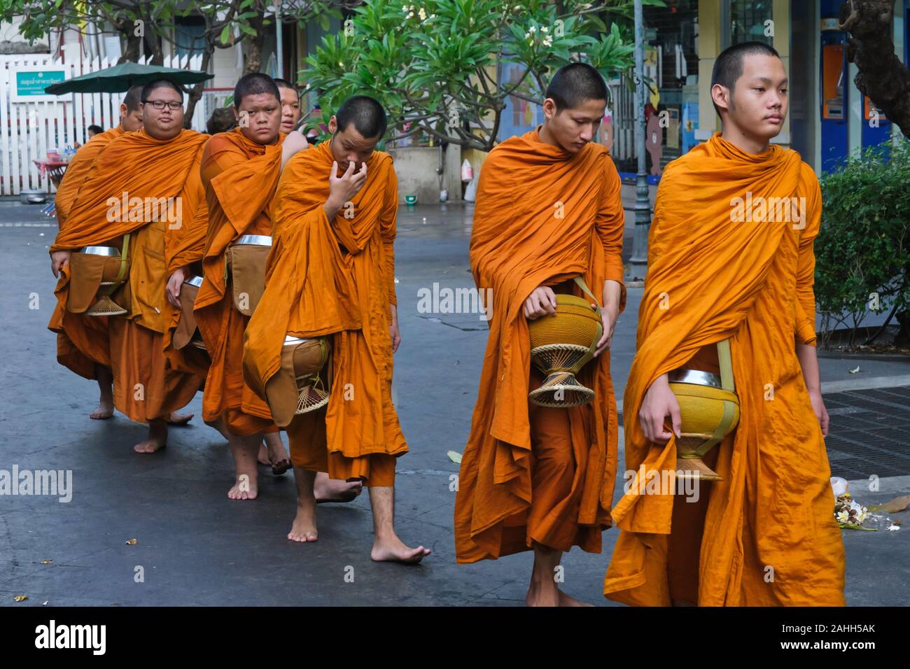 Jeune novice moines bouddhistes résident à Wat Mahathat à Bangkok, Thaïlande, avec leurs aumônes bols sur leur droit coutumier matin alms à pied Banque D'Images