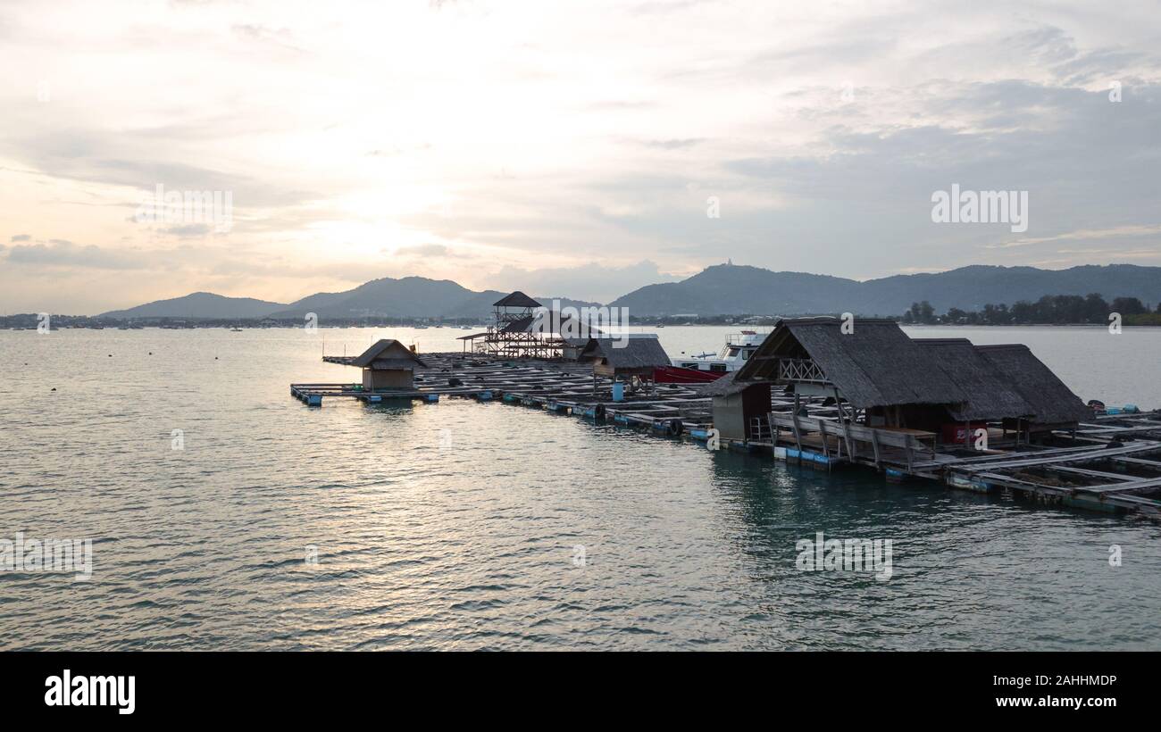 Thai fish farm sur le centre sur la mer loin de la côte, soft golden sunset over mountain on background Banque D'Images