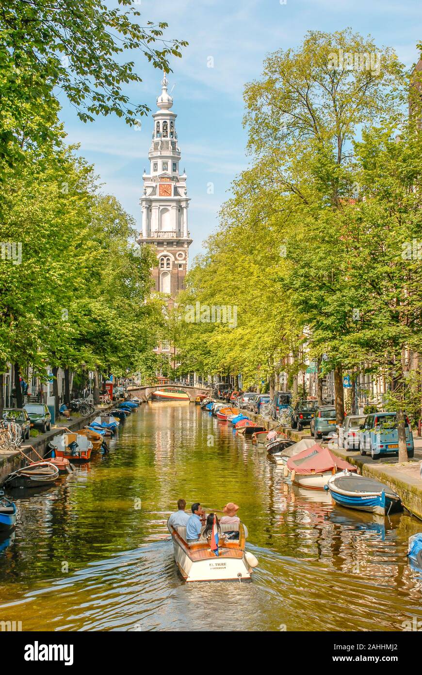 Petit bateau à moteur dans un canal d'eau à Amsterdam, Pays-Bas avec l'Oude Kerk en arrière-plan Banque D'Images