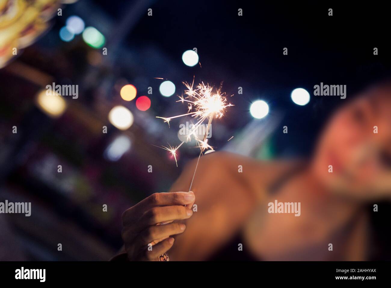 Dame tenir sa main firesparkler clignoter dans la nuit, tonifiant visage floue avec Banque D'Images