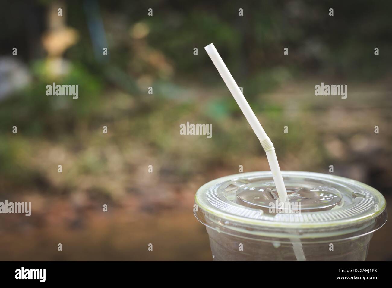 Tasse en plastique avec un peu de thé vert sur elle a quitter outdoor avec la nature en arrière-plan Banque D'Images