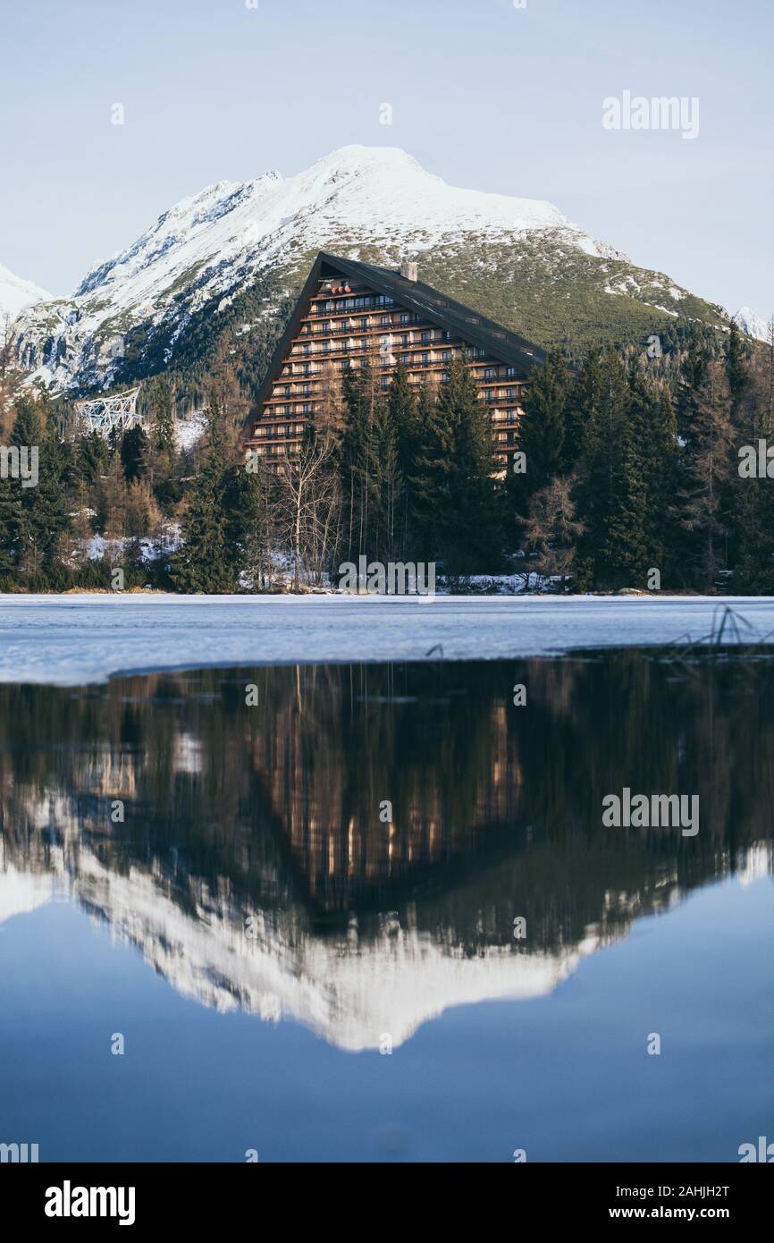 Strbske Pleso, Slovaquie - Décembre 2019 : vue sur l'hôtel Patria et hautes montagnes Tatras se reflétant dans l'eau du lac. Orientation verticale Banque D'Images