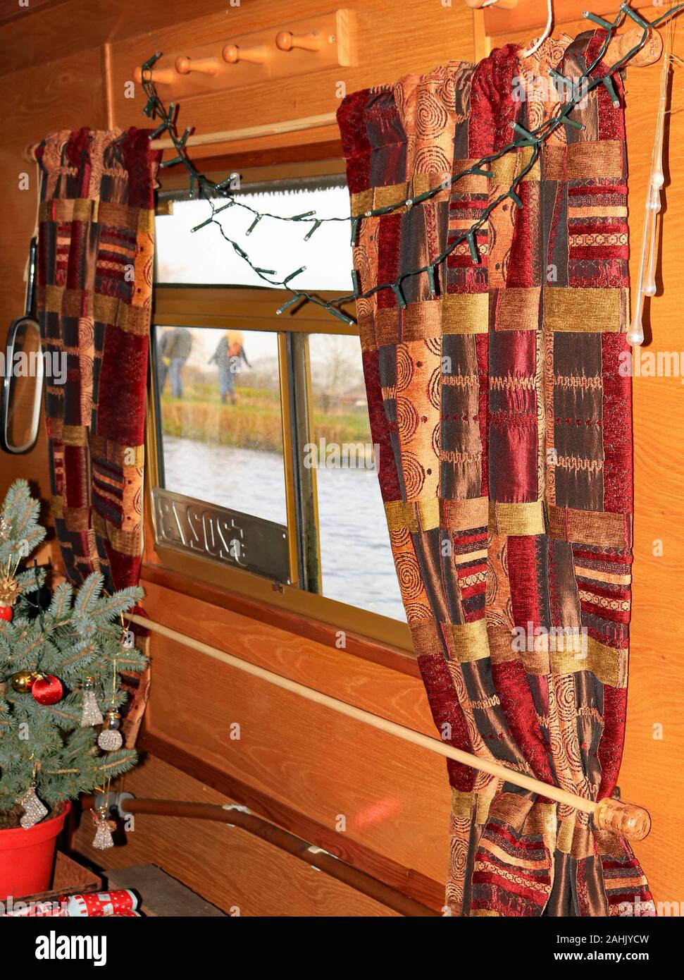 La nouvelle toile accrochée sur un petit bateau. Les rideaux sont ouverts, de manière à le voir dehors à l'eau et de halage peut être vu. Les rideaux sont suspendus sur rails en bois Banque D'Images