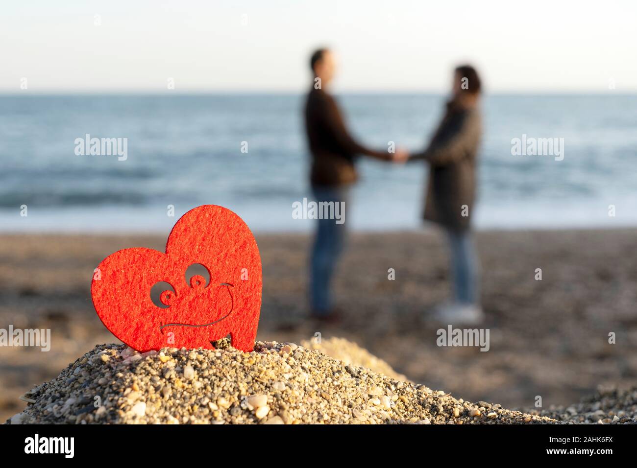 Cœur rouge sur une montagne de sable de la mer avec un couple d'amoureux dans l'arrière-plan. concept de san valentin Banque D'Images