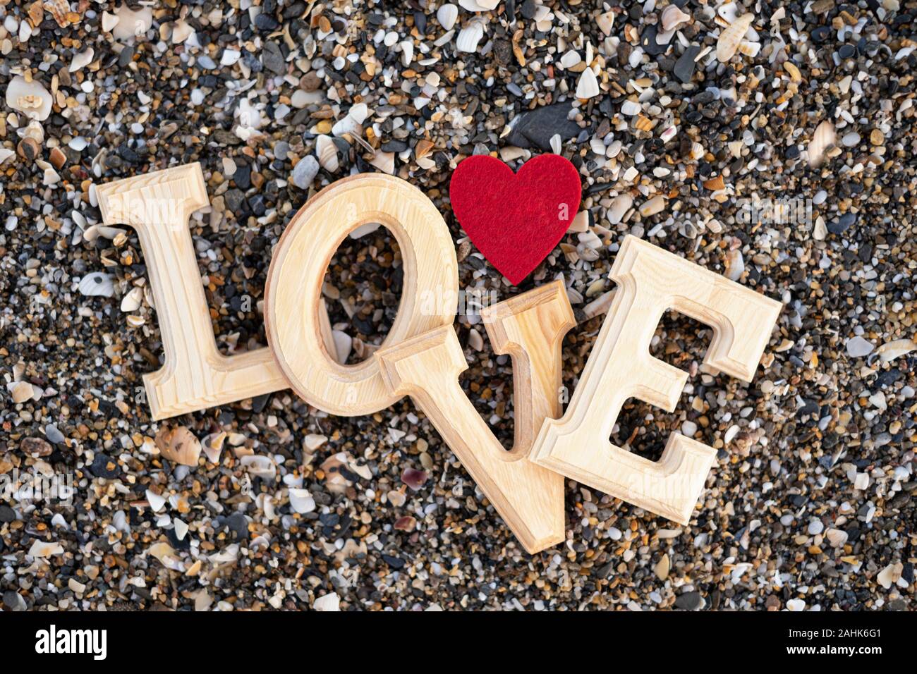 Lettres en bois formant le mot amour avec un cœur rouge sur un fond de sable de plage. concept de san valentin Banque D'Images