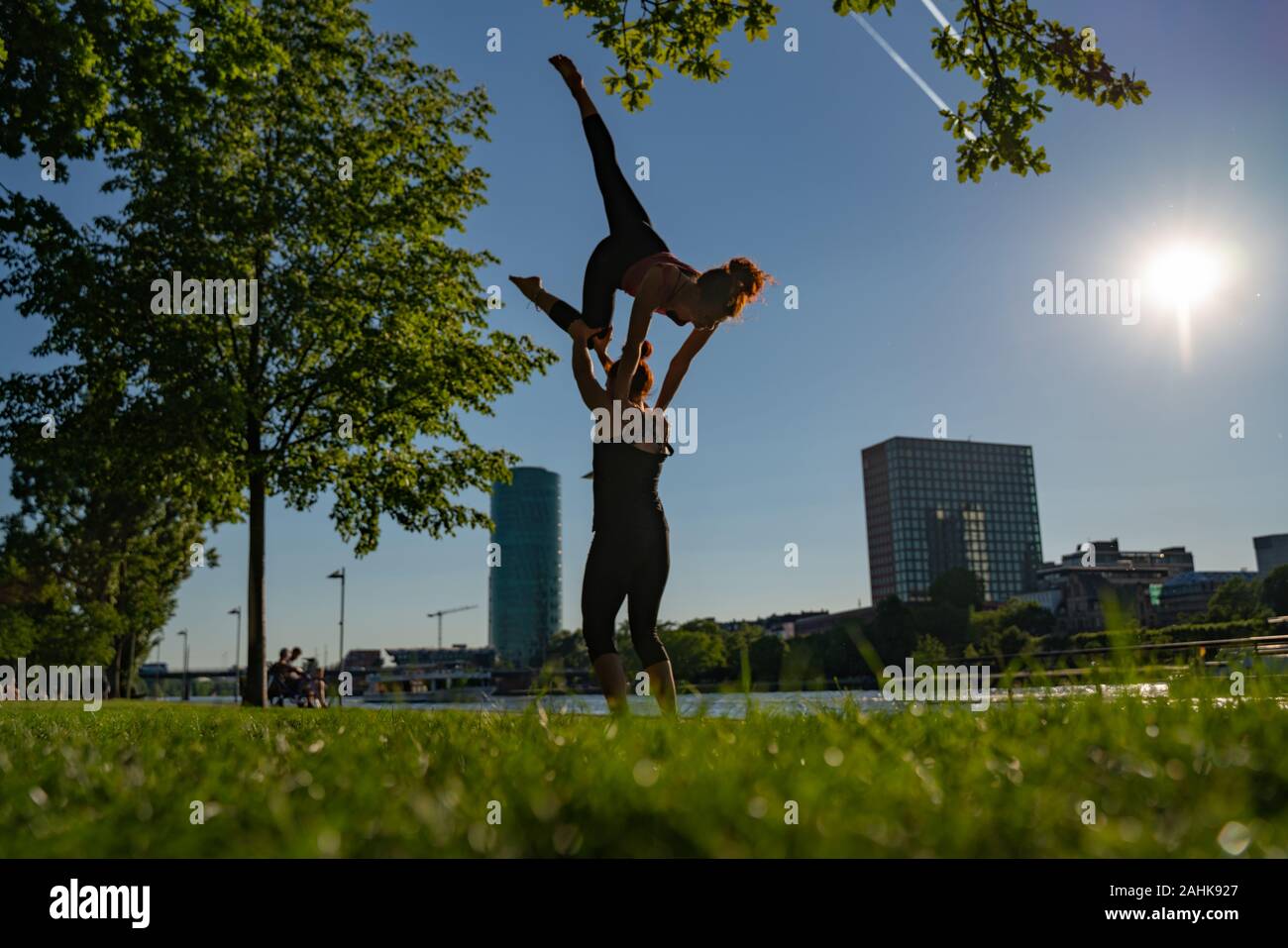 Deux jeunes filles n'acro yoga sur la rive du fleuve donnant sur la ville moderne. Jeunesse et Sport Banque D'Images