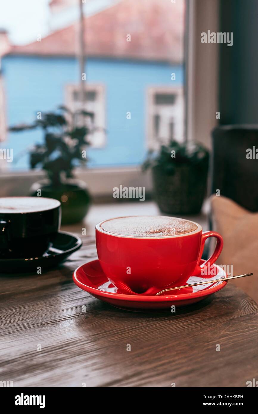 Céramique noire et rouge tasses de Cappuccino sur table en bois un café inn. Immersive pour votre conception. Close-up. Banque D'Images