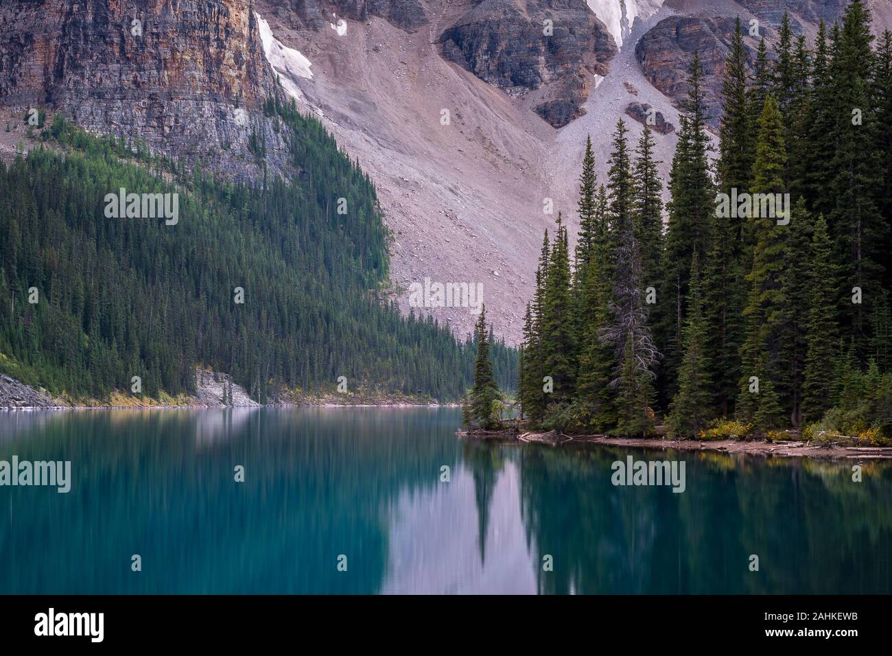 Superbe vue sur de grands arbres et montagne avec reflets dans l'eau bleu turquoise de l'eau du lac Moraine, Banff National Park, Alberta, Canada Banque D'Images