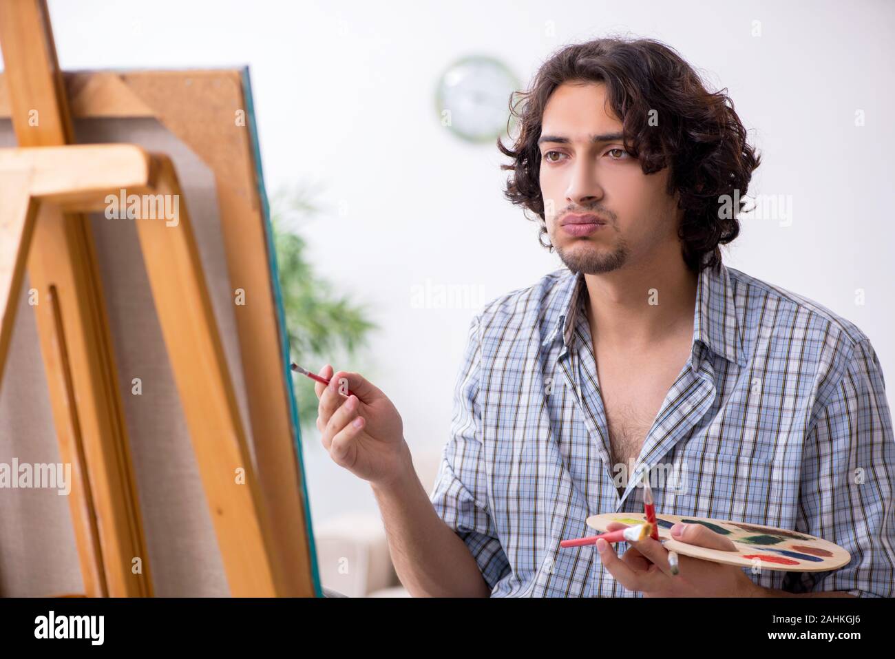 Le jeune homme séduisant appréciant la peinture à la maison Banque D'Images