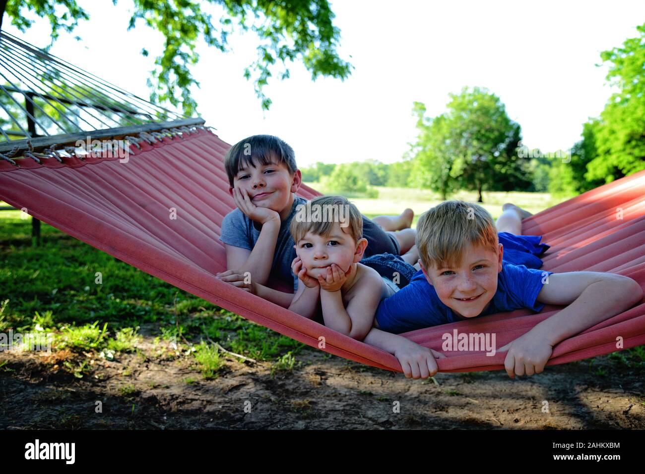 Trois garçons sur un hamac rouge Banque D'Images