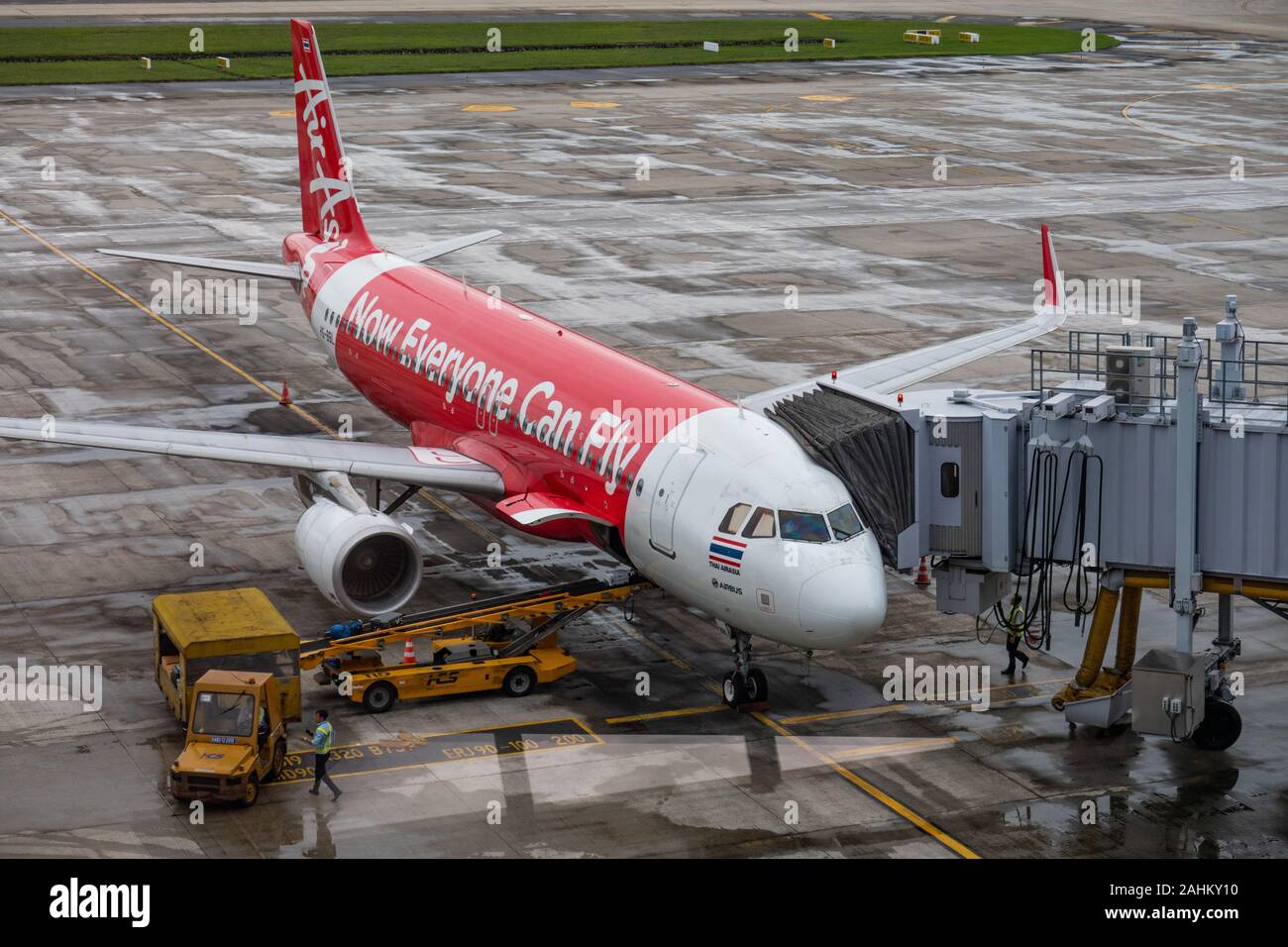 Un Airbus A320 de Thai AirAsia se trouve garé devant un portail et les personnels de charger les sacs sur un jour humide à Hanoi, l'Aéroport International de Noi Bai, Vietnam Banque D'Images