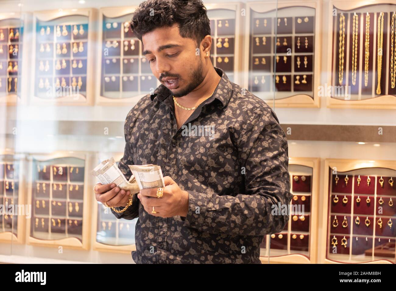 Concept de propriétaires de petites entreprises - jeune propriétaire ou l'entrepreneur au showroom bijoux argent comptant, montrant de profit et d'énormes ventes de gold. Banque D'Images