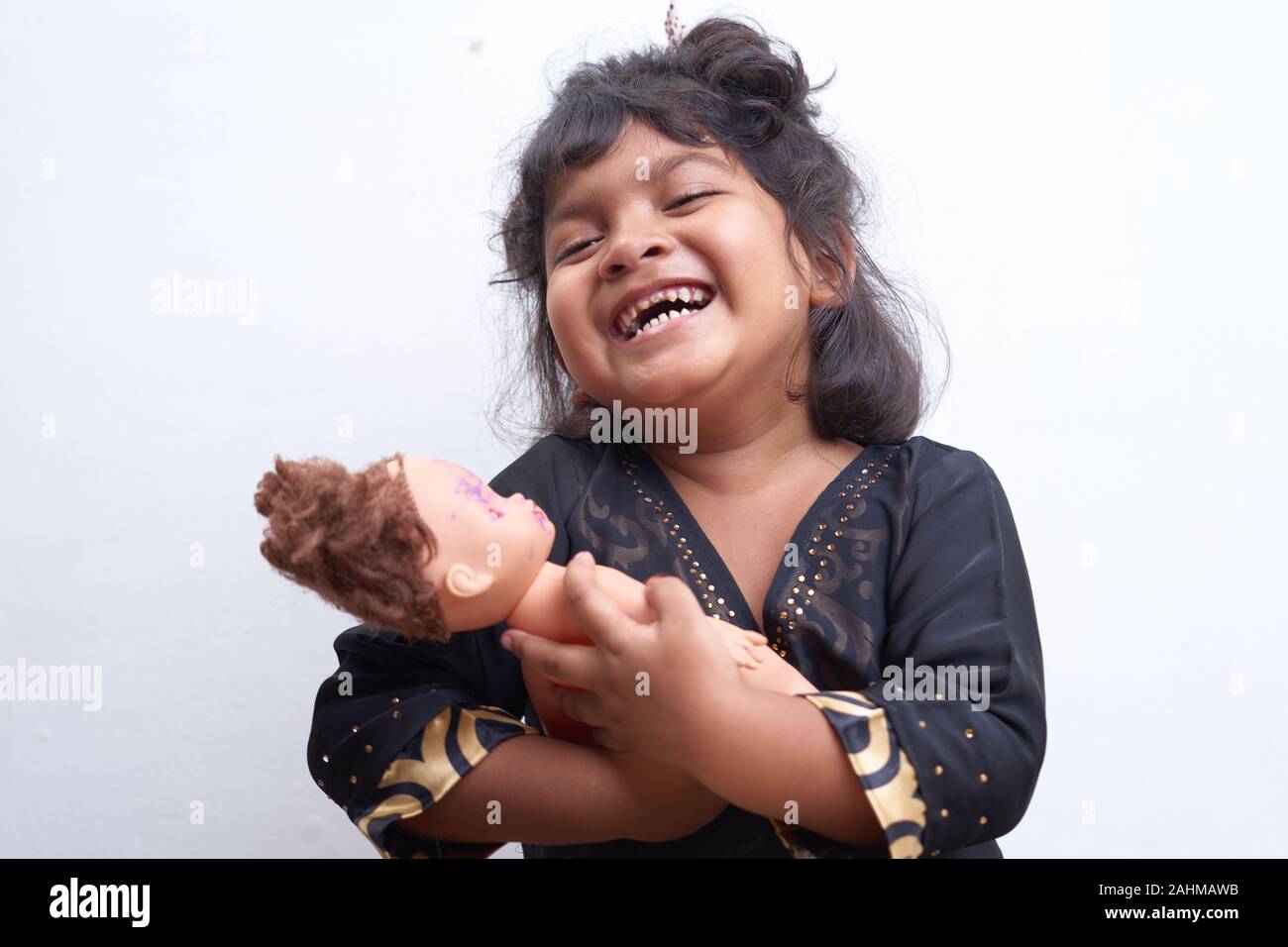 Petite fille asiatique comme une maman jouant avec une poupée sur fond blanc Banque D'Images