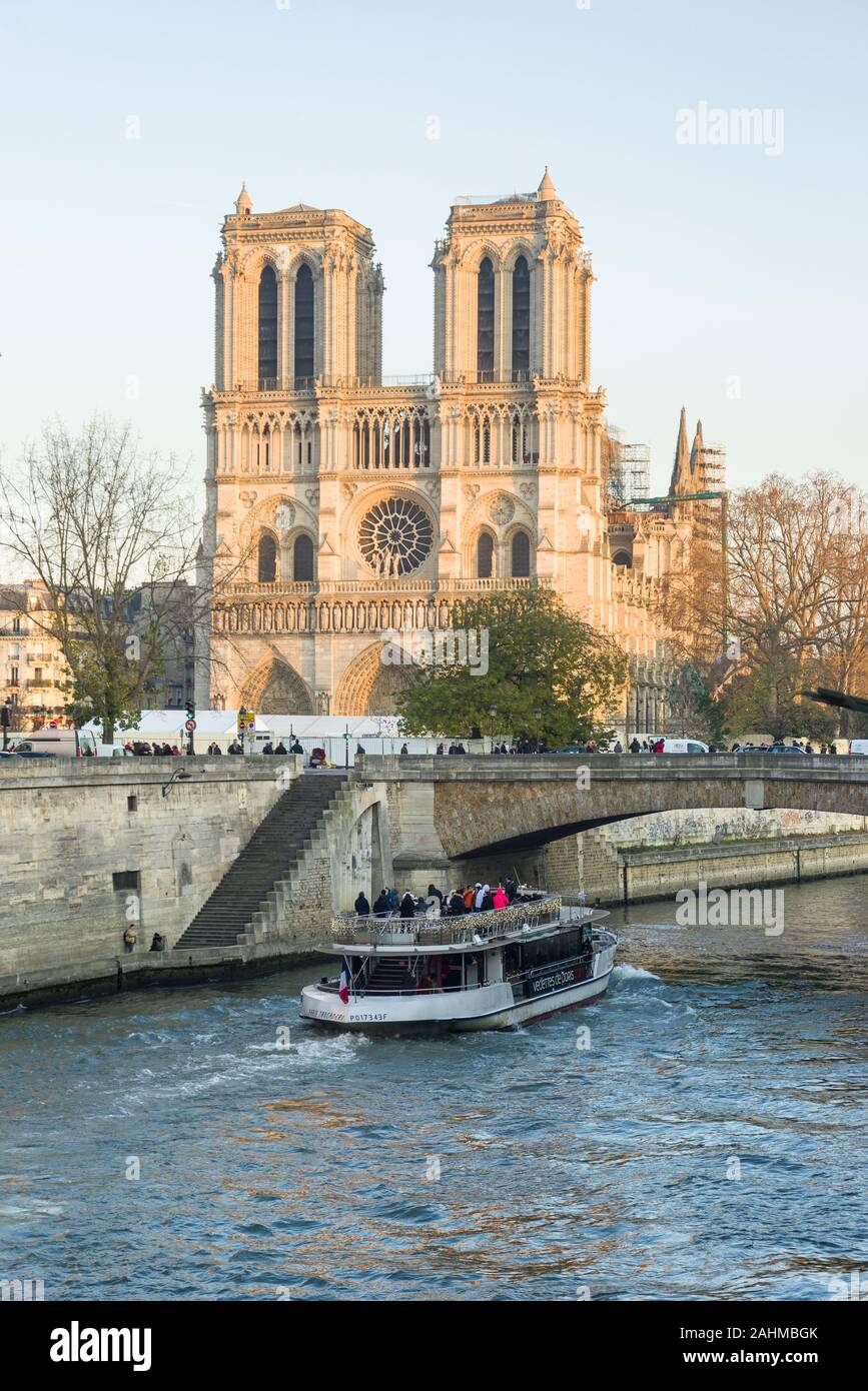 Extérieur de Cathédrale Notre-Dame de Paris avec croisière sur la Seine en premier plan sur une journée d'hiver ensoleillée, Paris, France Banque D'Images