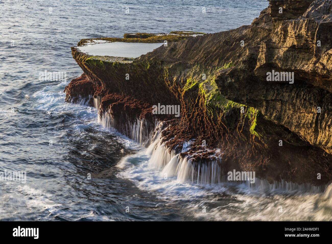 Rocheux au Devil's normale, sur la côte de Nusa Lembongan island, Bali, Indonésie. Piscine de marée au-dessus de la falaise rocheuse ; streaming l'eau des roches b Banque D'Images