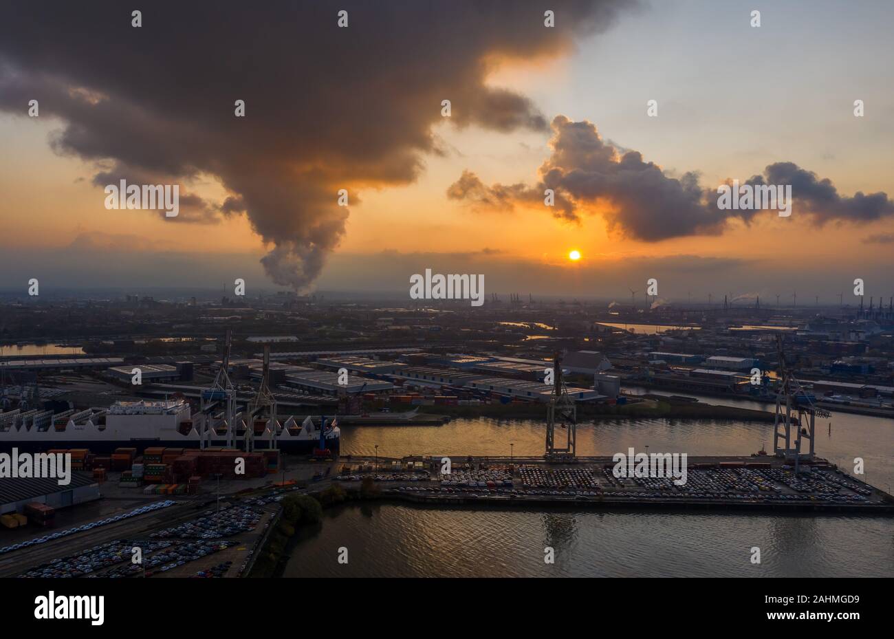 Drone aérien vue du port de Hambourg pendant le coucher du soleil avec de la fumée et des nuages lourds sur les chantiers par la mer Banque D'Images