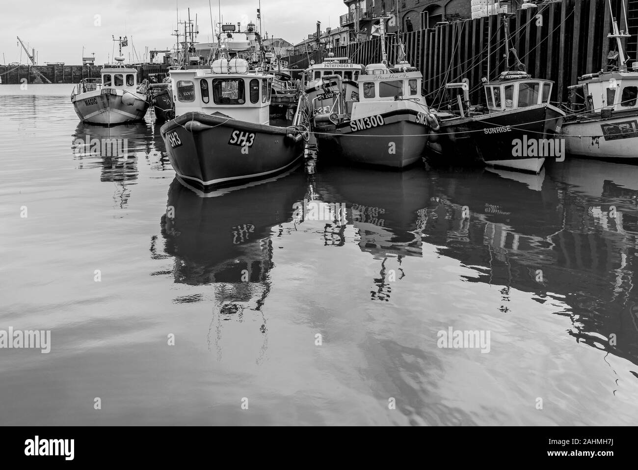 Le port de Scarborough. Les bateaux de pêche sont amarrés ensemble le long d'un quai. Leurs réflexions sont dans l'eau. Banque D'Images