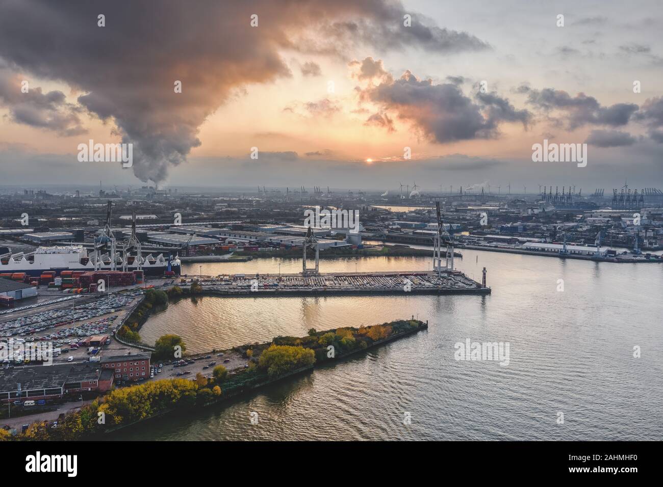 Drone aérien vue du port de Hambourg pendant le coucher du soleil avec de la fumée et des nuages lourds sur les chantiers par la mer Banque D'Images