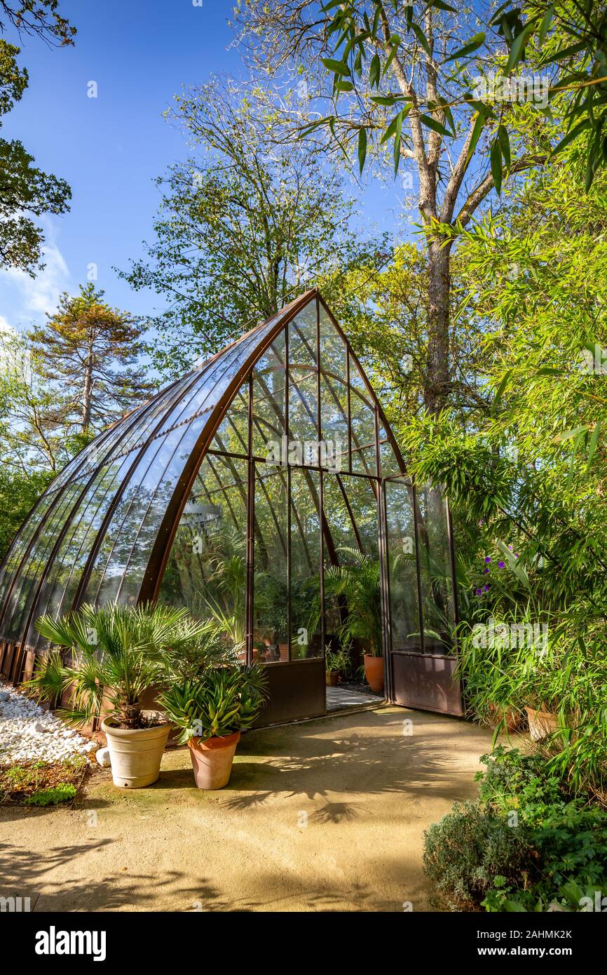 Belle maison en forme de pyramide de vert acier rouillé et de verre dans un jardin entouré d'arbres Banque D'Images
