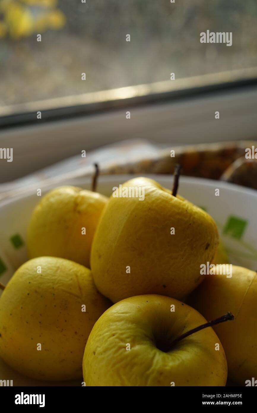 Vieux jaune naturel des pommes dans une assiette sur un rebord de fenêtre Banque D'Images
