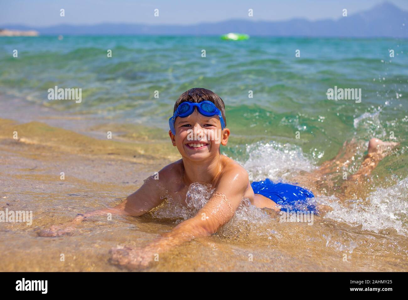 Petit enfant couché sur le sable dans l'eau de mer à la plage, des vacances Banque D'Images