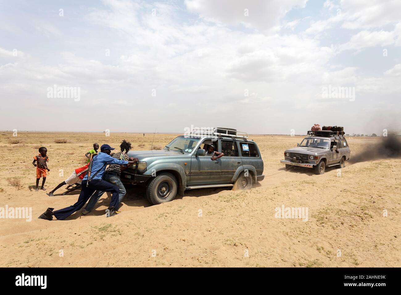 Les hommes armés poussent leur voiture coincée dans du sable doux près du lac turkana, à la frontière de l'Éthiopie et du Kenya Banque D'Images