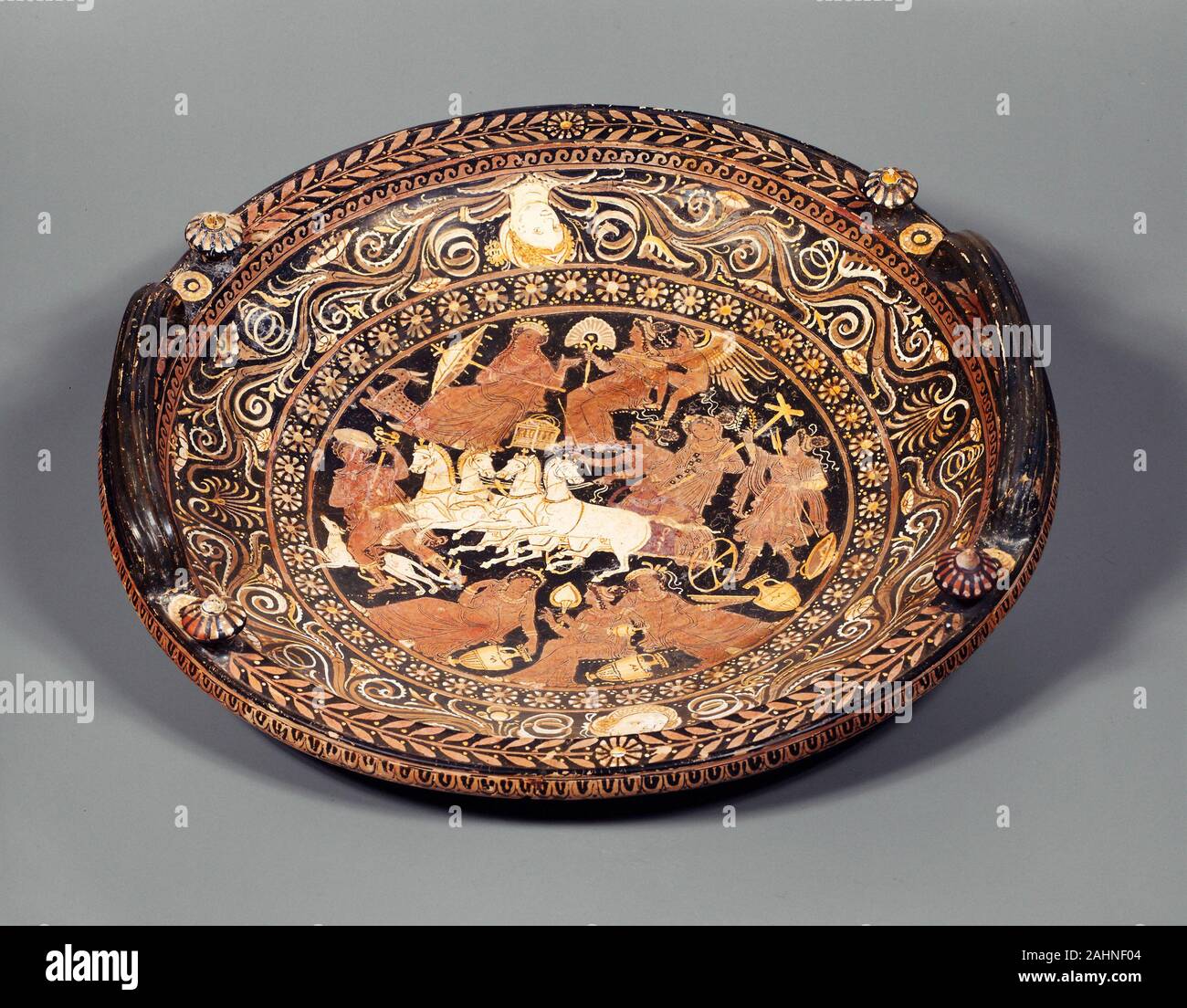 Le grec ancien. Knob-Handled Patera (plat). 330-320 av. J.-C.-B. Pouilles. sols en terre cuite, décoré dans la red-figure technique Le plat circulaire avec boutons aux côtés de ses poignées est typiquement un navire des Pouilles. Une patera est généralement utilisé pour verser des libations, mais cet exemple est particulièrement grand. Des bandes de largeur variable contenant des motifs répétitifs et défilement vrilles interrompue par les femmes chefs entourent une scène centrale Hermes, le dieu des voyageurs, la récolte principale déesse Déméter et sa fille Perséphone de la pègre, où la jeune fille avait été retenu en captivité par Hadès. Perseph Banque D'Images Le grec ancien. Knob-Handled Patera (plat). 330-320 av. J.-C.-B. Pouilles. sols en terre cuite, décoré dans la red-figure technique Le plat circulaire avec boutons aux côtés de ses poignées est typiquement un navire des Pouilles. Une patera est généralement utilisé pour verser des libations, mais cet exemple est particulièrement grand. Des bandes de largeur variable contenant des motifs répétitifs et défilement vrilles interrompue par les femmes chefs entourent une scène centrale Hermes, le dieu des voyageurs, la récolte principale déesse Déméter et sa fille Perséphone de la pègre, où la jeune fille avait été retenu en captivité par Hadès. Perseph Banque D'Images