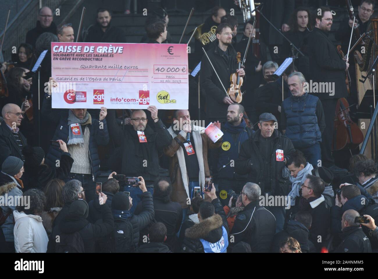 *** Strictement AUCUNE VENTES À DES MÉDIAS OU DES ÉDITEURS FRANÇAIS *** 31 décembre 2019 - Paris, France : Des manifestants montrent un chèque géant de 40.000 euros qui symbolise le montant d'argent que l'Infocom CGT, une direction générale de l'Union européenne, donnera à l'opéra les travailleurs en grève. Les musiciens de l'Opéra Bastille ouvrait le concert en plein air sur les marches de l'opéra pour protester contre le fait que le gouvernement français plan de réforme des pensions. Banque D'Images