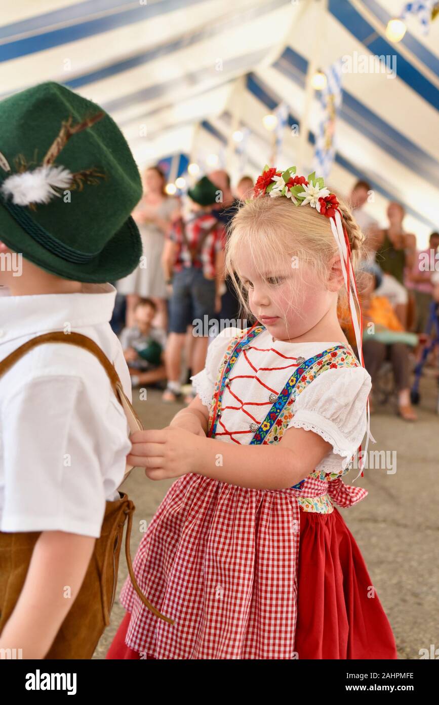 Une jeune fille mignonne en robe dirndl tenant des jarretelles de son frère à Oktoberfest à New Glarus, Wisconsin, États-Unis Banque D'Images