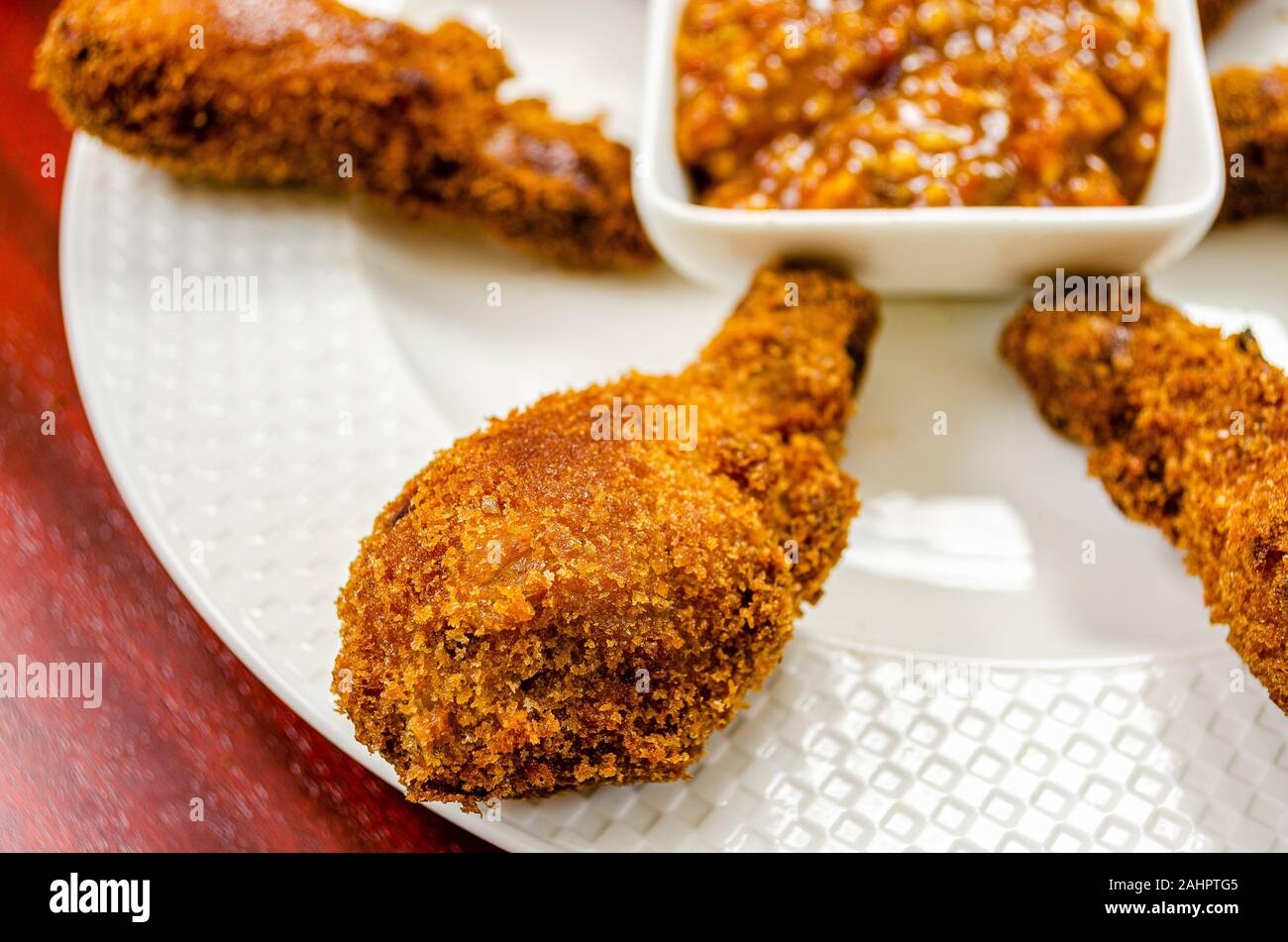 Pilons de poulet dans une assiette blanche avec sauce trempette épicée Banque D'Images