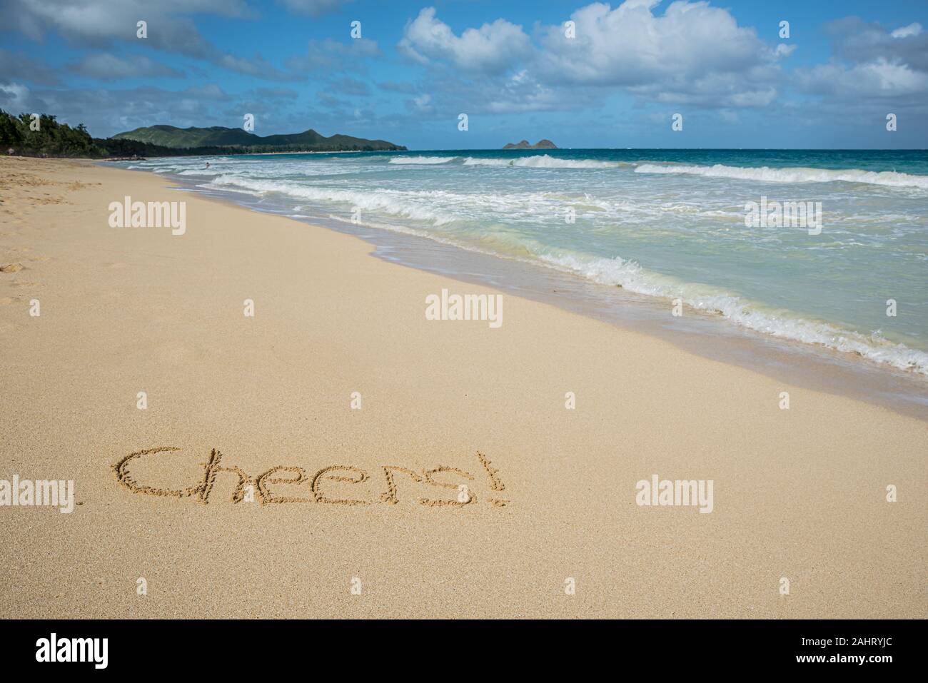 Cheers écrit dans le sable sur Waimanalo Beach à Hawaii avec l'océan en arrière-plan Banque D'Images