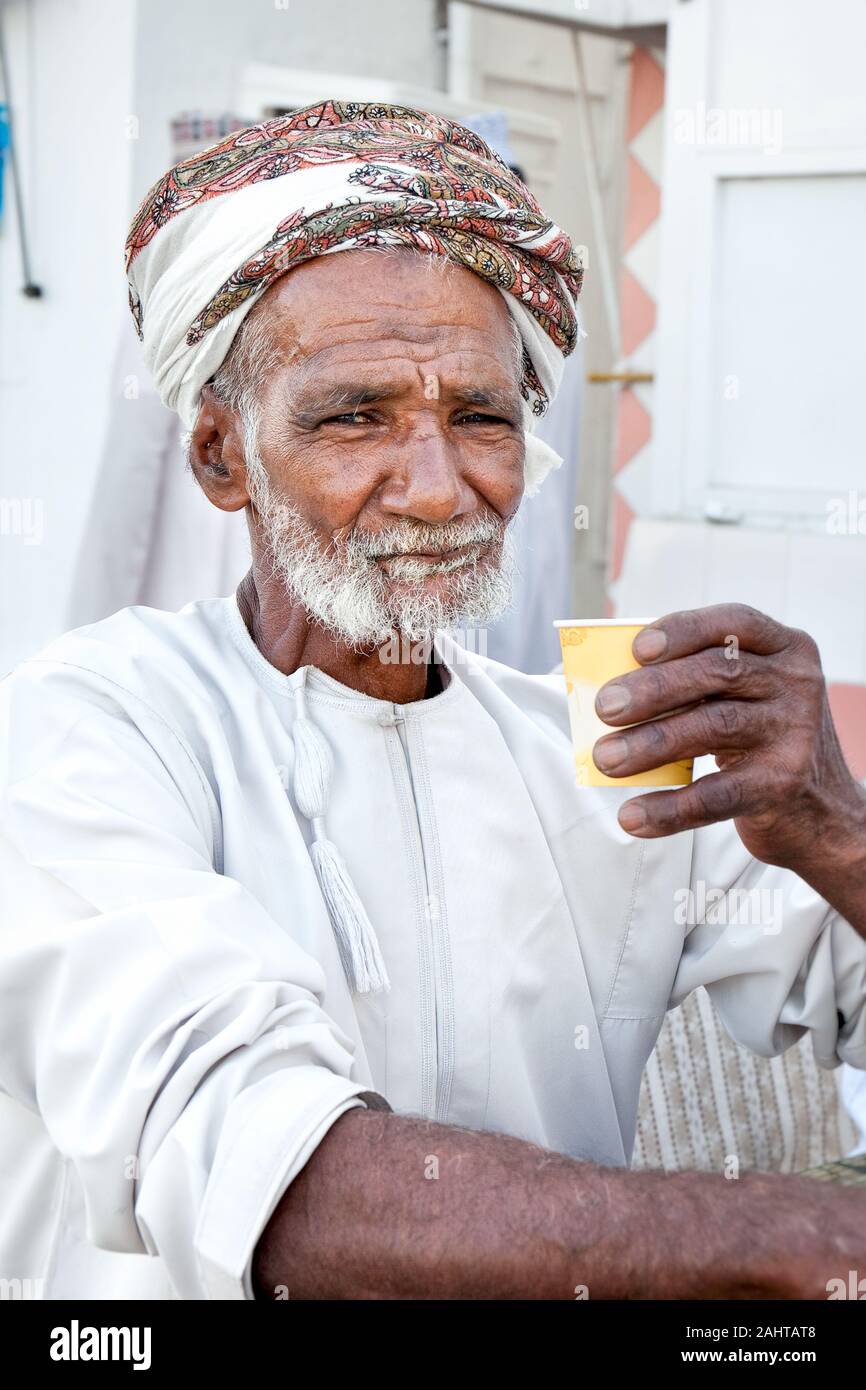 Un homme omanais de boire du café, avec une barbe grise porte un mussar traditionnel sur la tête. Muscat, Oman. Banque D'Images