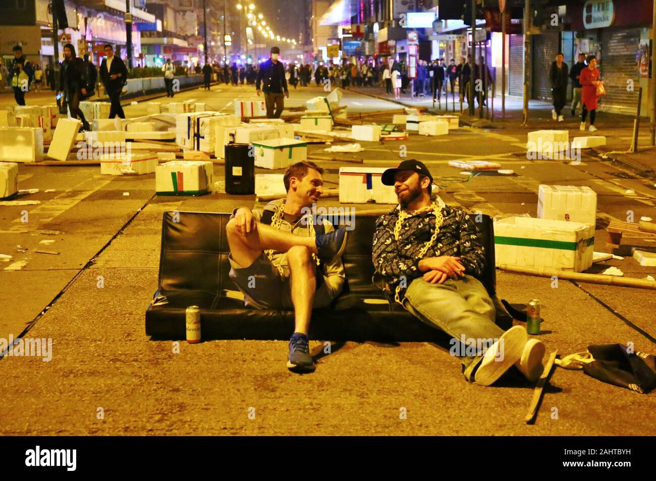 Hong Kong, Chine. 25, décembre 2019. Noël à Hong Kong est marquée par des manifestations et désobéissance civile. Deux hommes ont de la bière dans un canapé à gauche après les émeutes à l'arrêt. Banque D'Images
