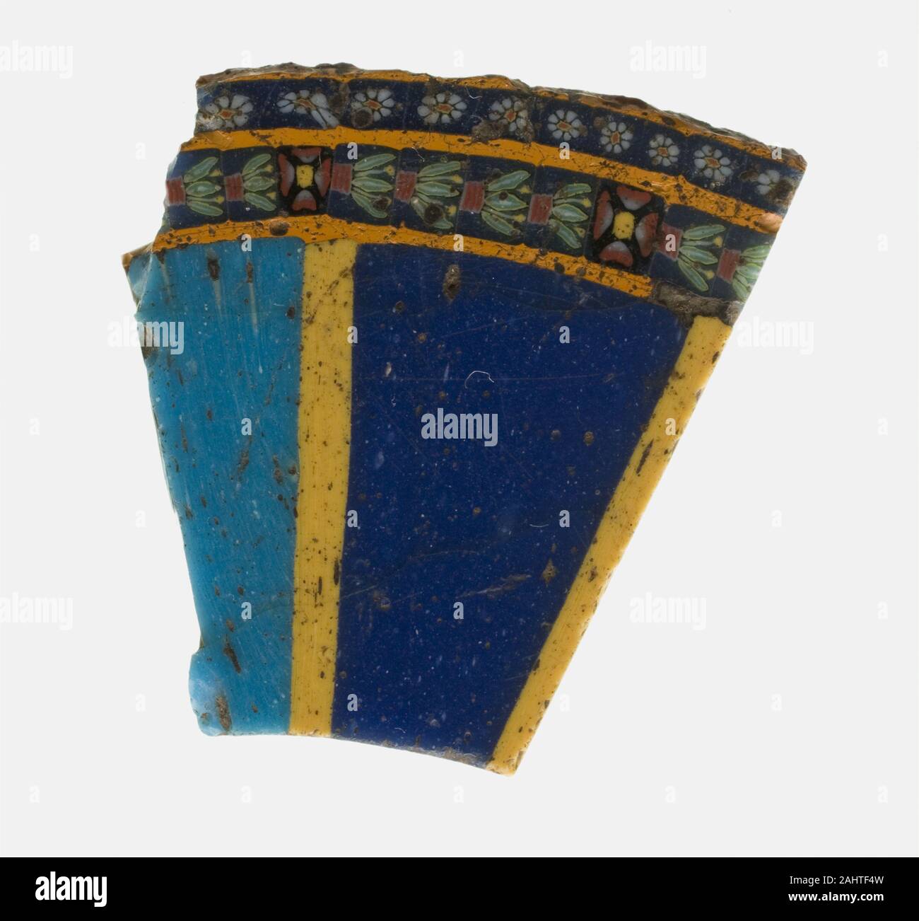 Egypte antique. Fragment d'une jaquette (peut-être partie d'un collier). 100 BC-AD 100. Région méditerranéenne. Une technique de mosaïque de verre, verre de la mosaïque a été faite de faisceaux de tiges en verre de couleur qui ont été présentées sous forme d'un schéma puis fusionné avec chaleur dans une canne solide. La canne était réchauffé et étiré pour faire un plus petit modèle compact. De nombreuses pièces presque identiques pourraient être réduits à partir d'une seule canne et alors disposé en incrustations. Le fragment avec une double rangée de fleurs minuscules sur son bord pourraient avoir fait partie d'une marqueterie représentant un large collier porté par un roi ou un dieu. Banque D'Images