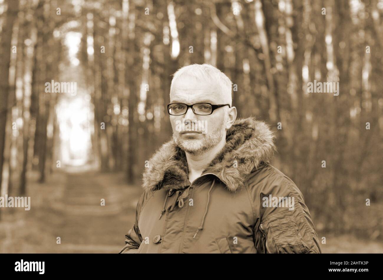 Closeup portrait d'un homme intelligent avec les cheveux gris et des lunettes, une barbe dans une veste d'hiver. Tonification, sépia. Banque D'Images