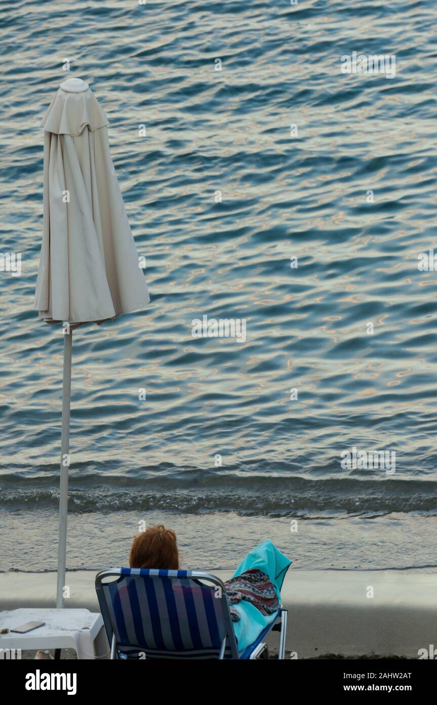 Une femme se trouve dans une chaise longue sous une couverture sur le bord  de la mer.La fin de la saison. L'automne à la station. Symbole de solitude, de  nostalgie et de