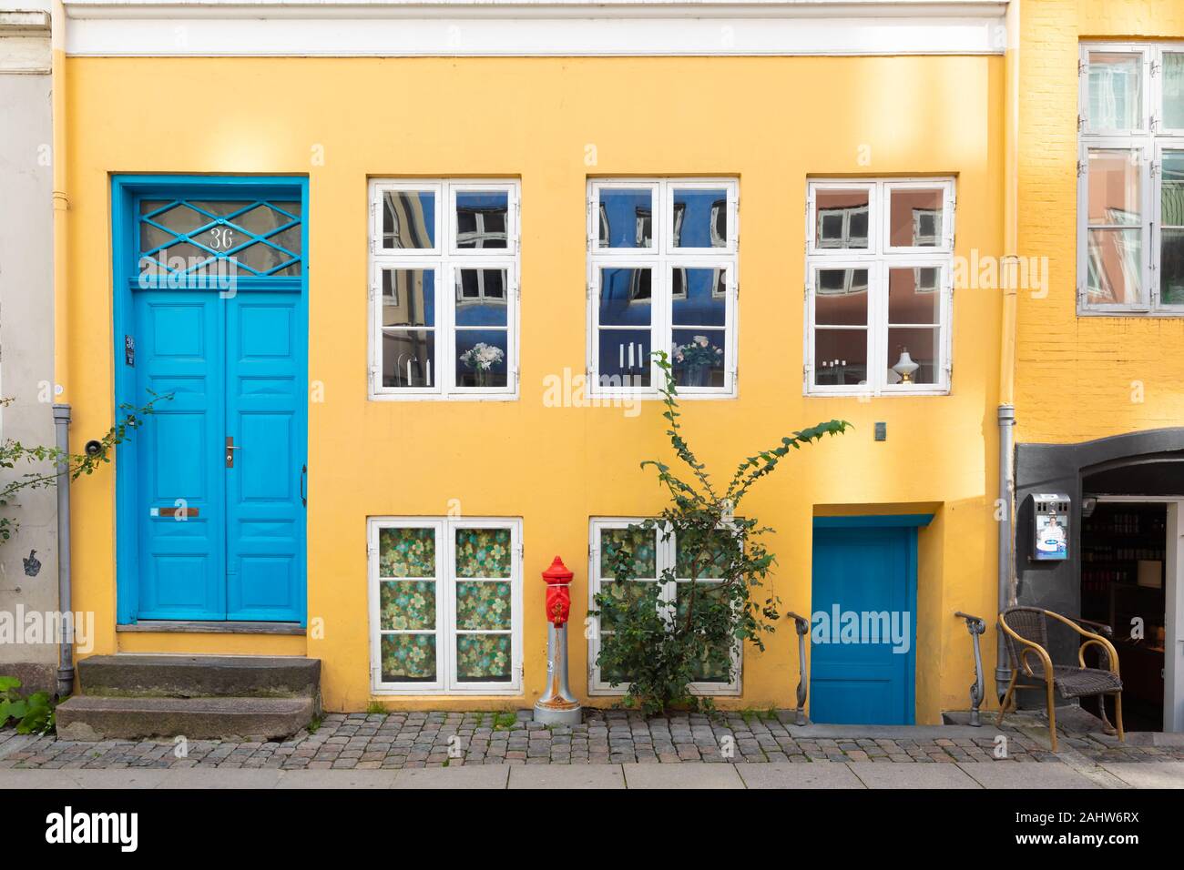 Copenhague, Danemark : Art et coloré jaune / orange maison de ville peint bleu et blanc avec portes fenêtres encadrées par une chaussée pavée. Banque D'Images