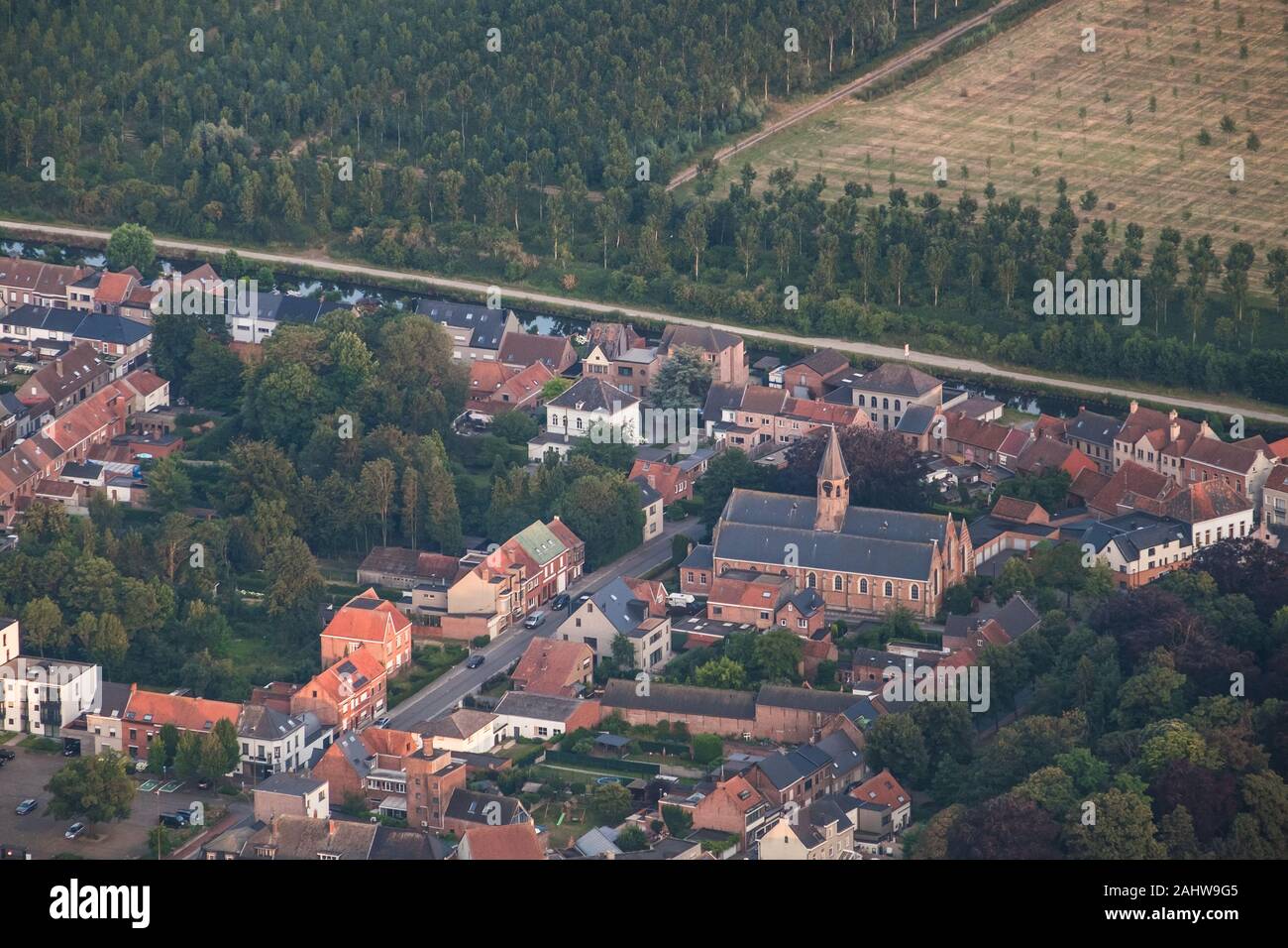 L'église de Saint Antoine, domine l'horizon de Moerbeke en Flandre-Orientale. Derrière, un canal et des rangées d'arbres forment une transition vers une région rurale. Banque D'Images