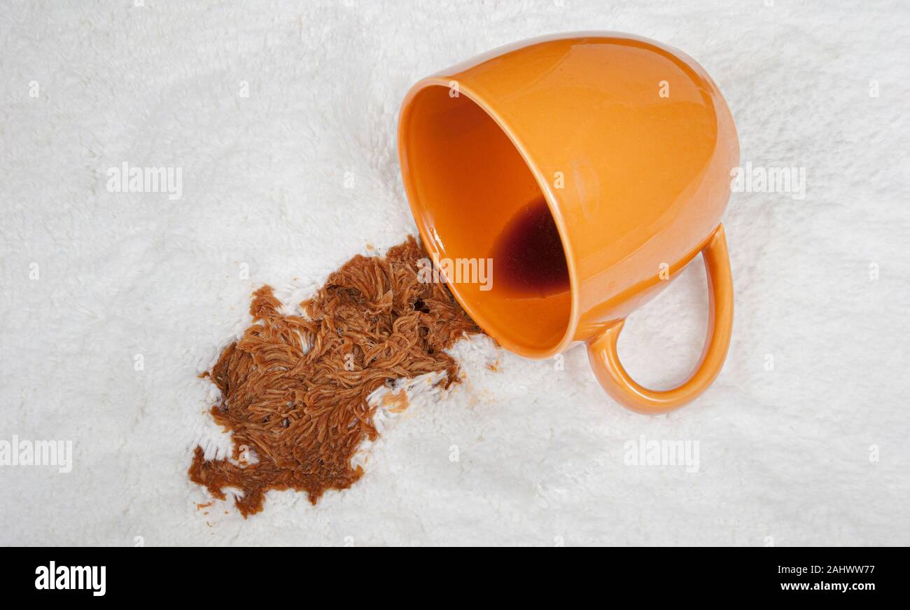 Coup horizontal d'une tasse de café renversé sur le tapis blanc. Banque D'Images Coup horizontal d'une tasse de café renversé sur le tapis blanc. Banque D'Images