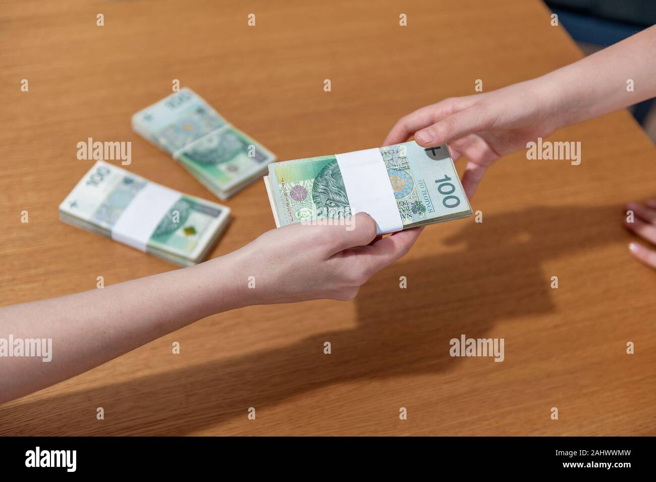 Main femme pile d'origine polonaise à la femme la main. Arrière-plan de table en bois avec des tas d'argent. Les billets d'argent polonais Banque D'Images