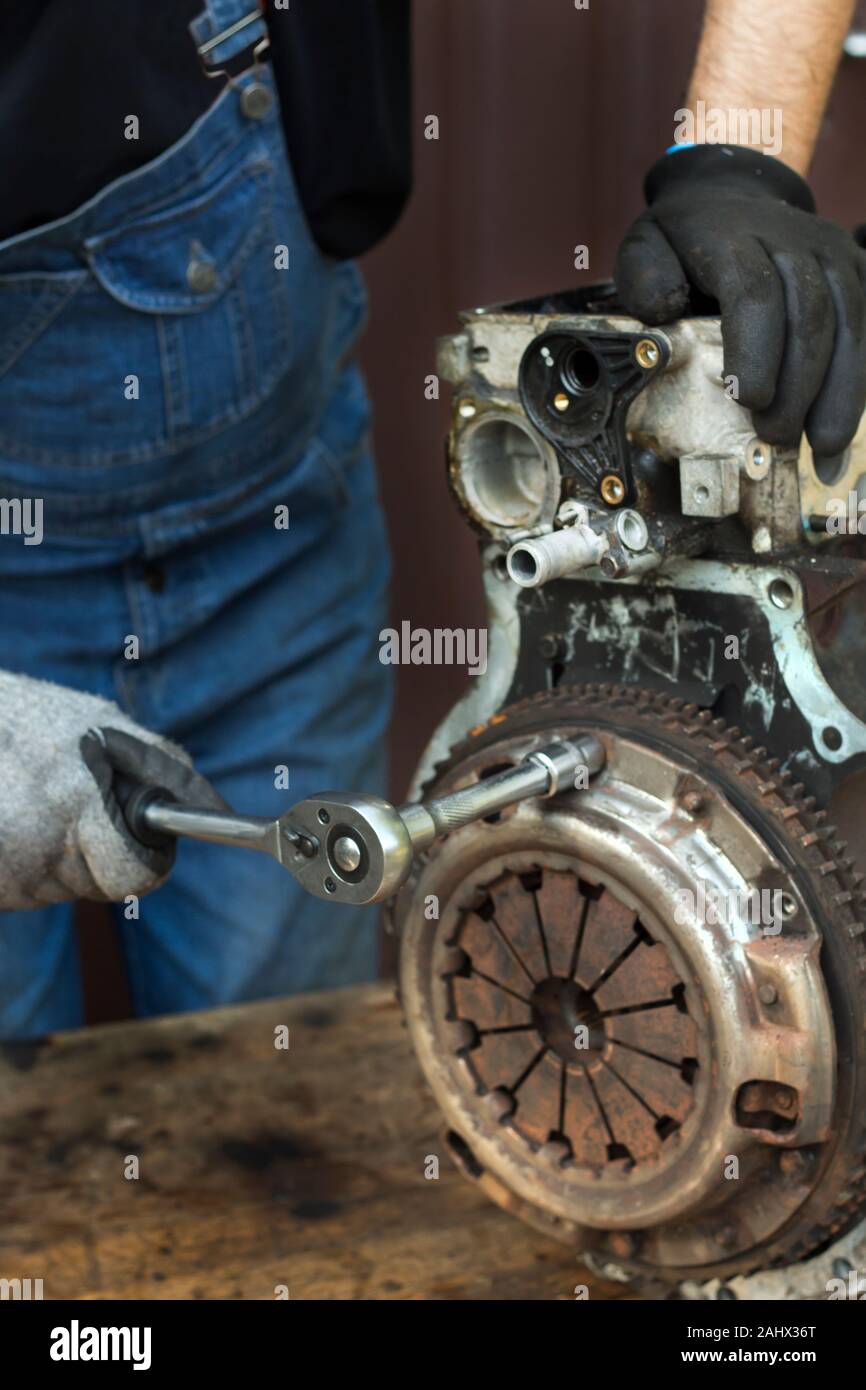 Gants de travail mécanicien de voiture dans l'embrayage se dévisse du bloc moteur au cours de la réparation à l'atelier. Banque D'Images
