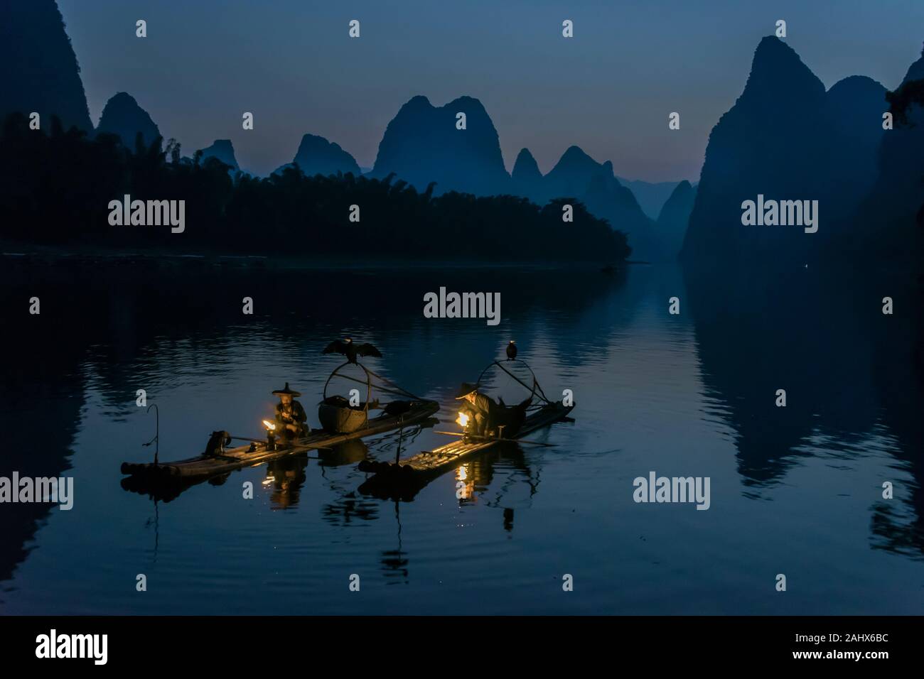 Deux pêcheurs cormorans éclairent leurs lanternes tôt le matin, Li River, Xingping, Guilin, Chine Banque D'Images