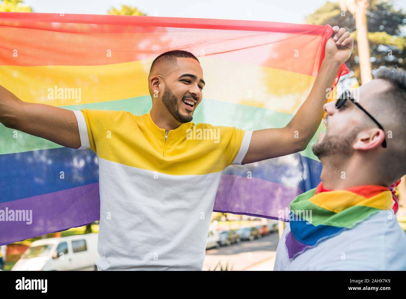 Portrait of young couple embracing et montrant leur amour avec drapeau arc-en-ciel dans le stret. Amour LGBT et concept. Banque D'Images
