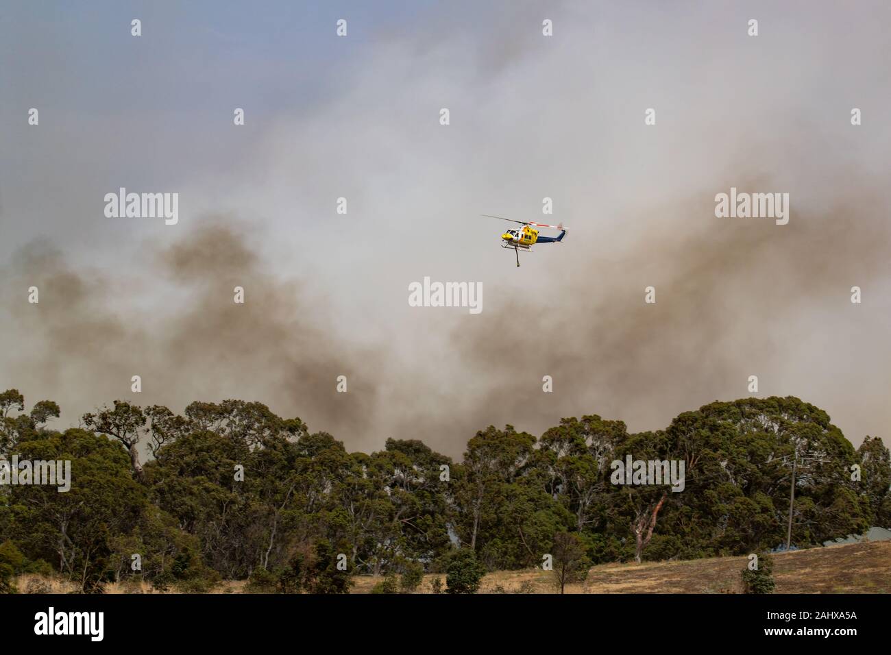 Vol en hélicoptère Bell 412 contre les panaches de fumée pendant la lutte contre les feux de brousse dans la région de Victoria, en Australie. Banque D'Images