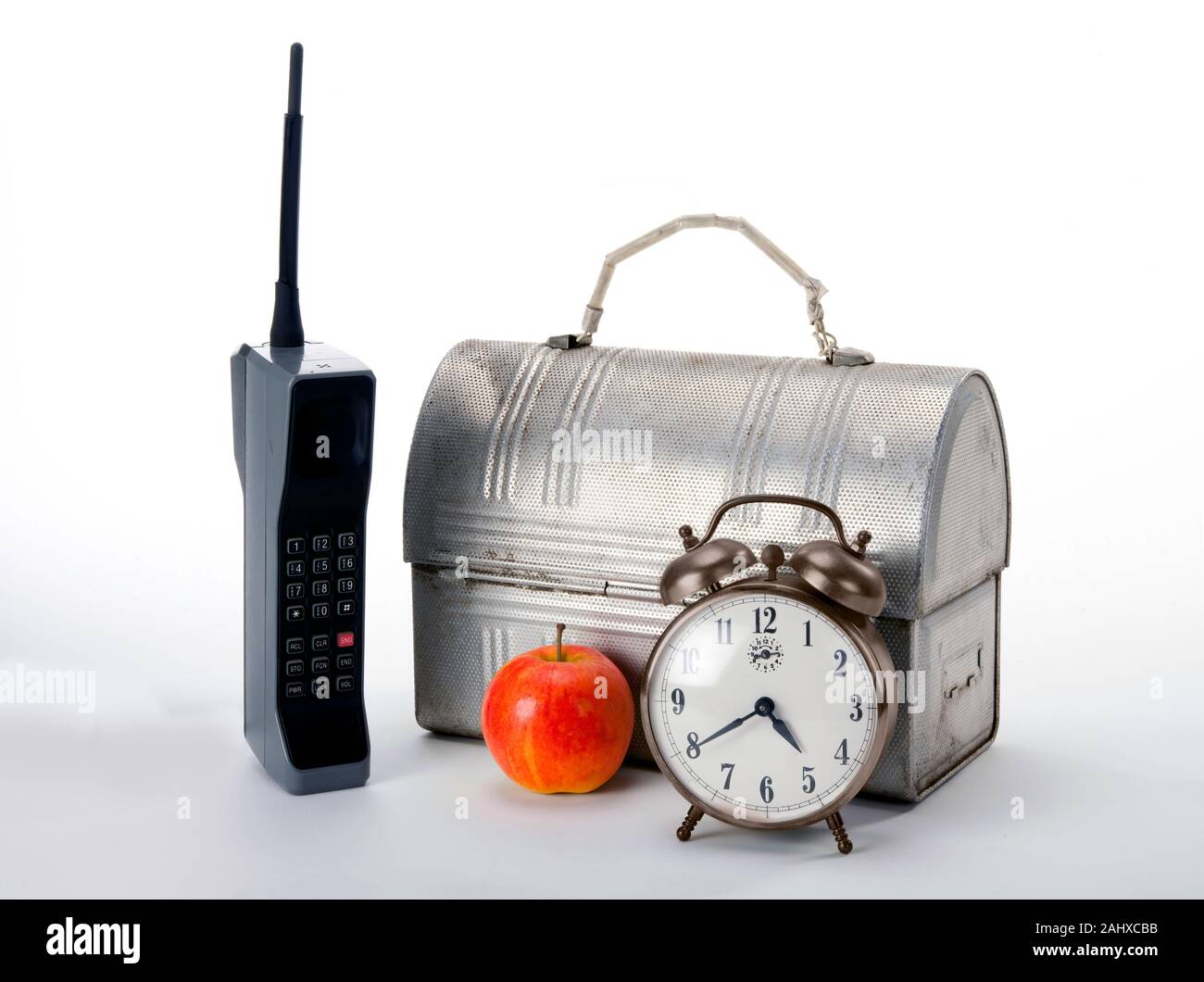Temps de travail dans les années 1980 avec téléphone cellulaire en brique rouge et boîte à lunch apple. Banque D'Images