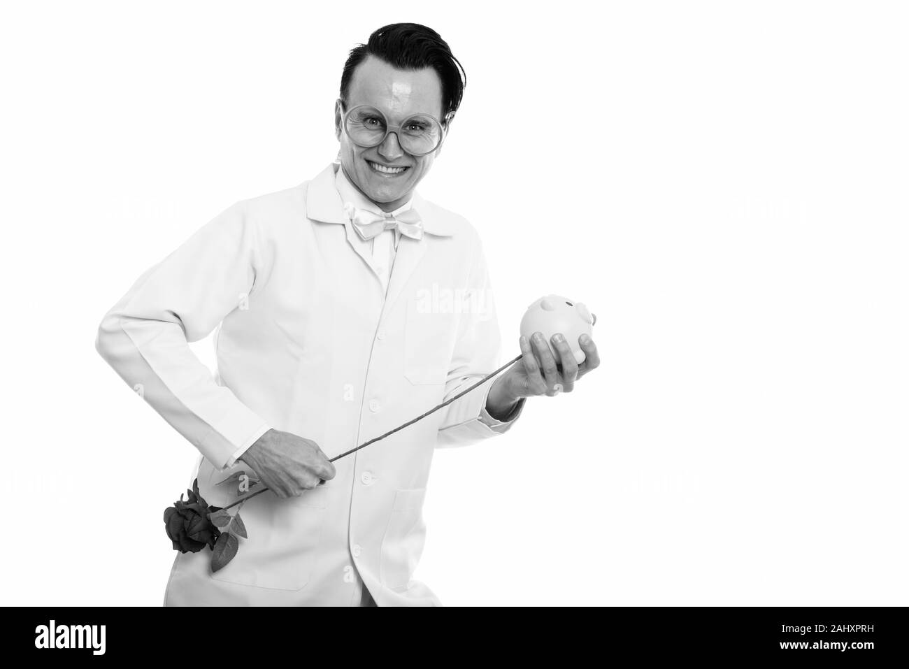 Studio shot of happy crazy man smiling médecin tout en poignardant rose rouge à l'intérieur de Piggy Bank Banque D'Images