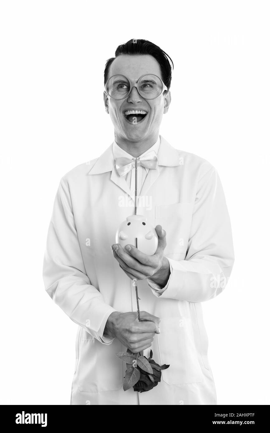 Studio shot of happy crazy man doctor smiling en pensant et rose rouge à l'intérieur de Piggy Bank Banque D'Images
